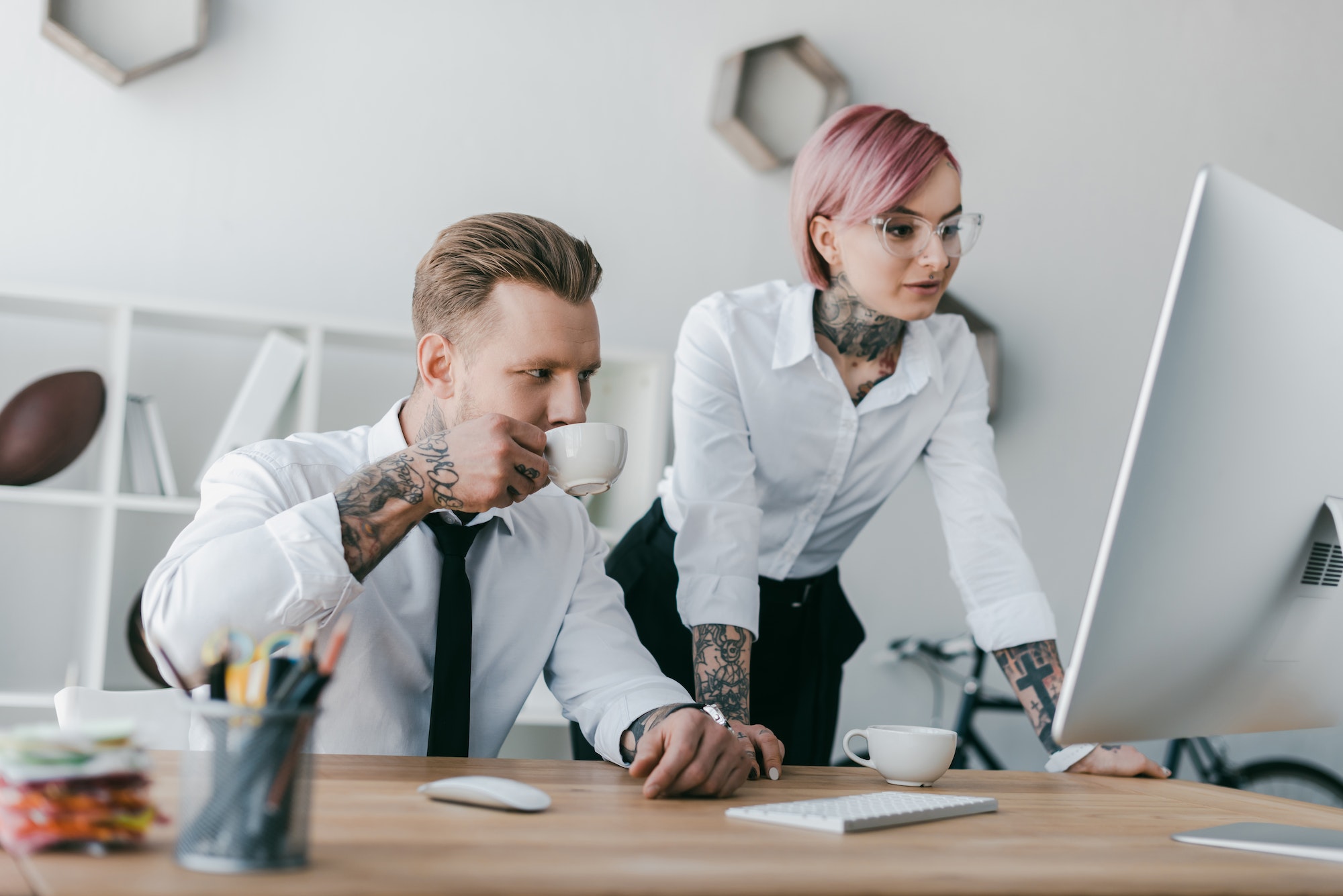 young tattooed business people using desktop computer together